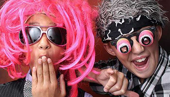 Two people with pink hair and one has a fake skull on his forehead.