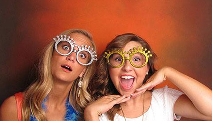 Two women wearing funny glasses posing for a picture.
