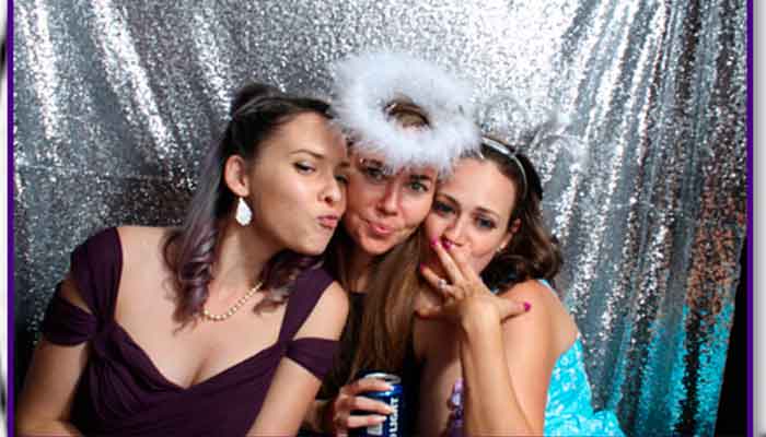Three women posing for a photo in front of a silver background.