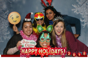 A group of people posing for a picture in front of a happy holidays sign.