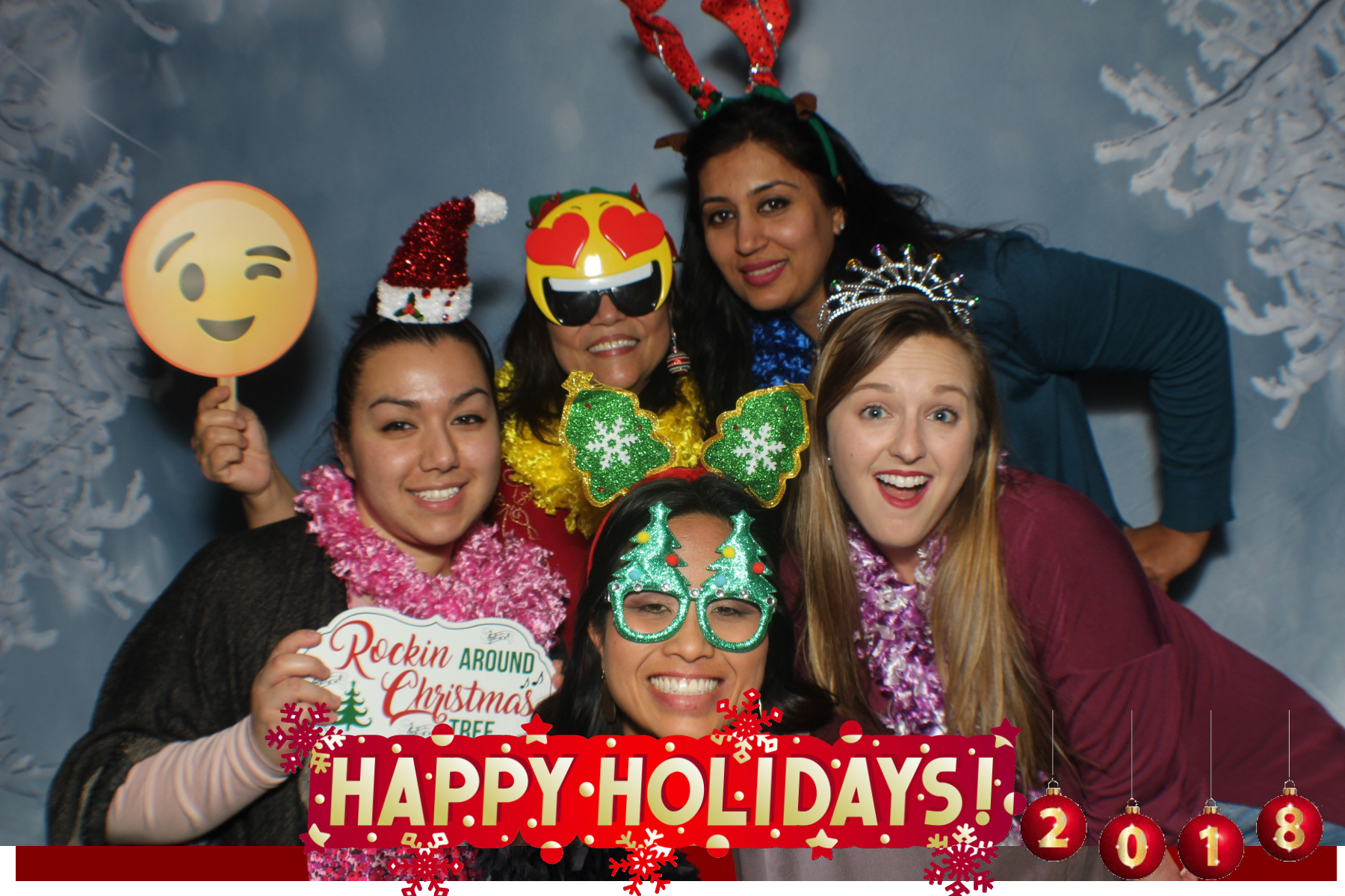 A group of people posing for a picture in front of a happy holidays sign.
