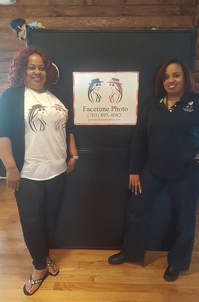 Two women standing next to a black sign.