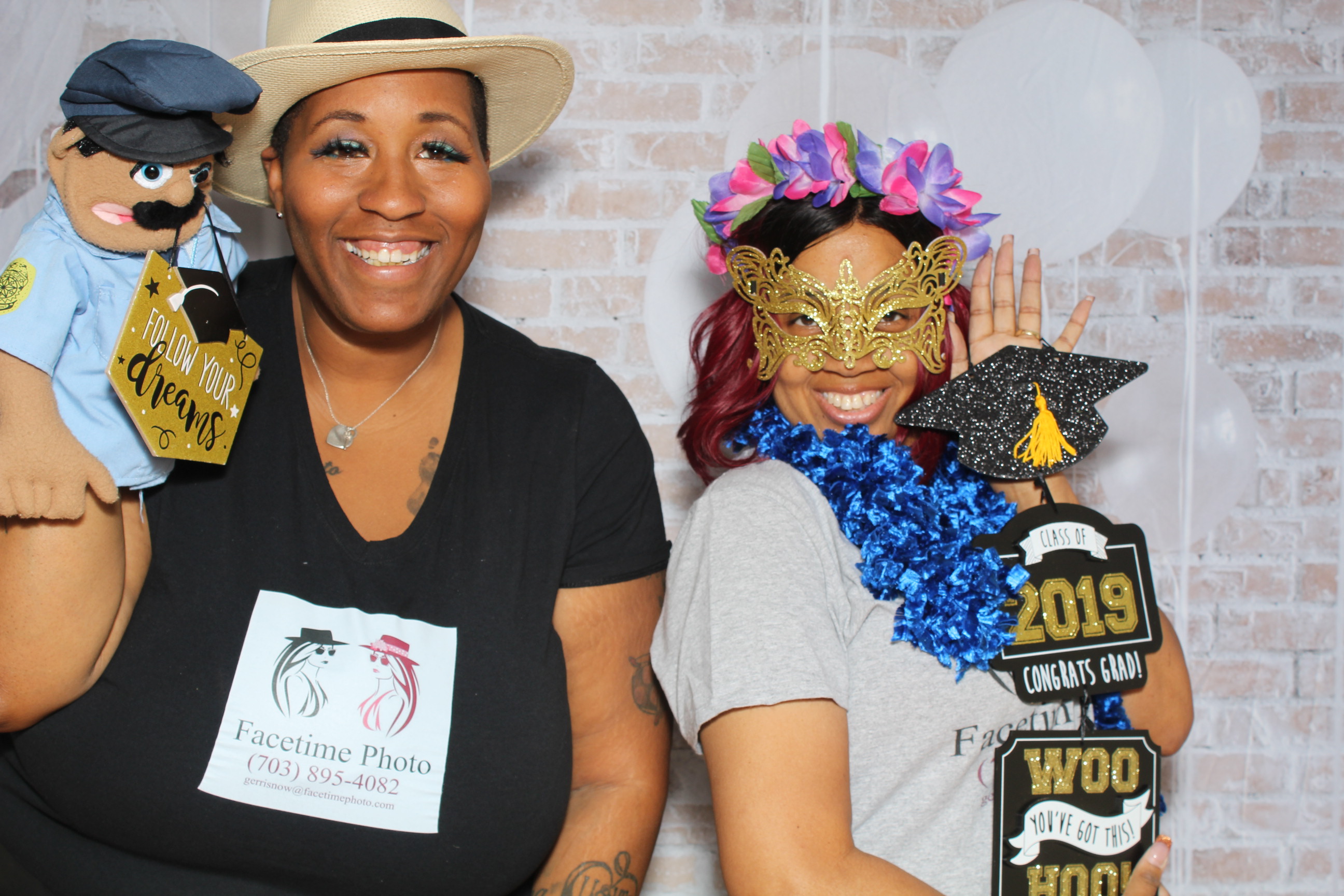 Two women posing for a picture in front of a brick wall.
