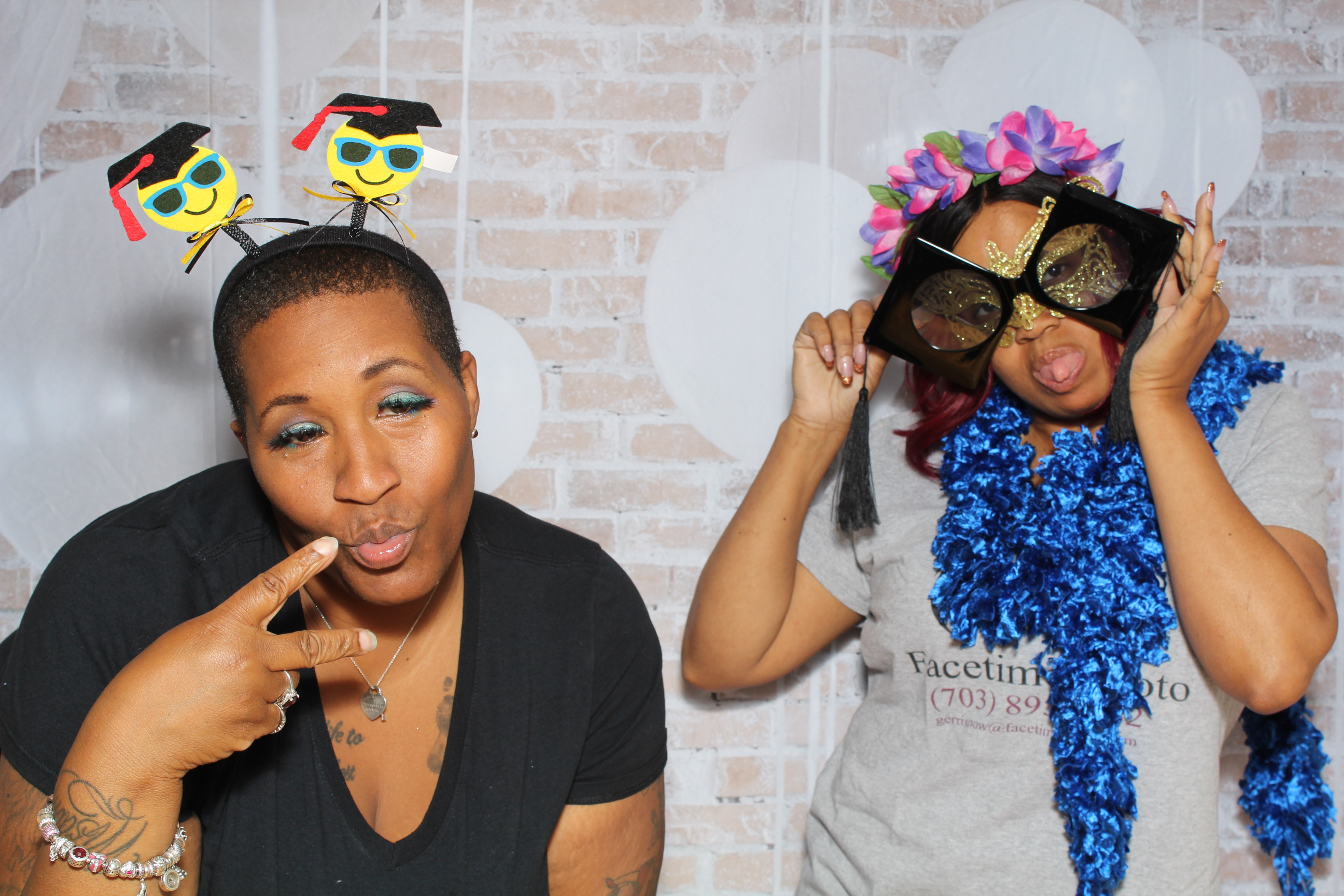 Two women posing for a photo in front of a brick wall.