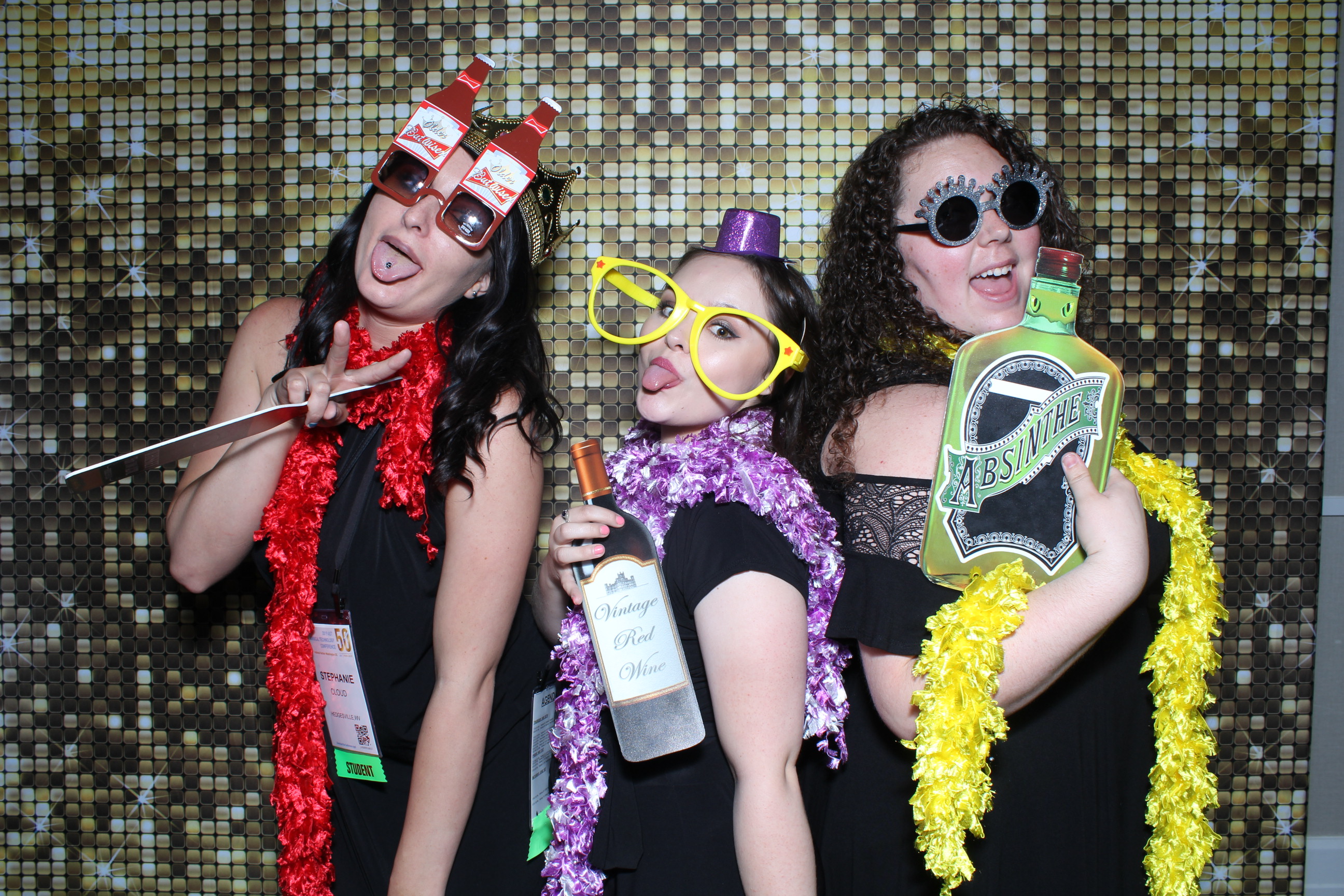 Three women posing for a photo in front of a wall.
