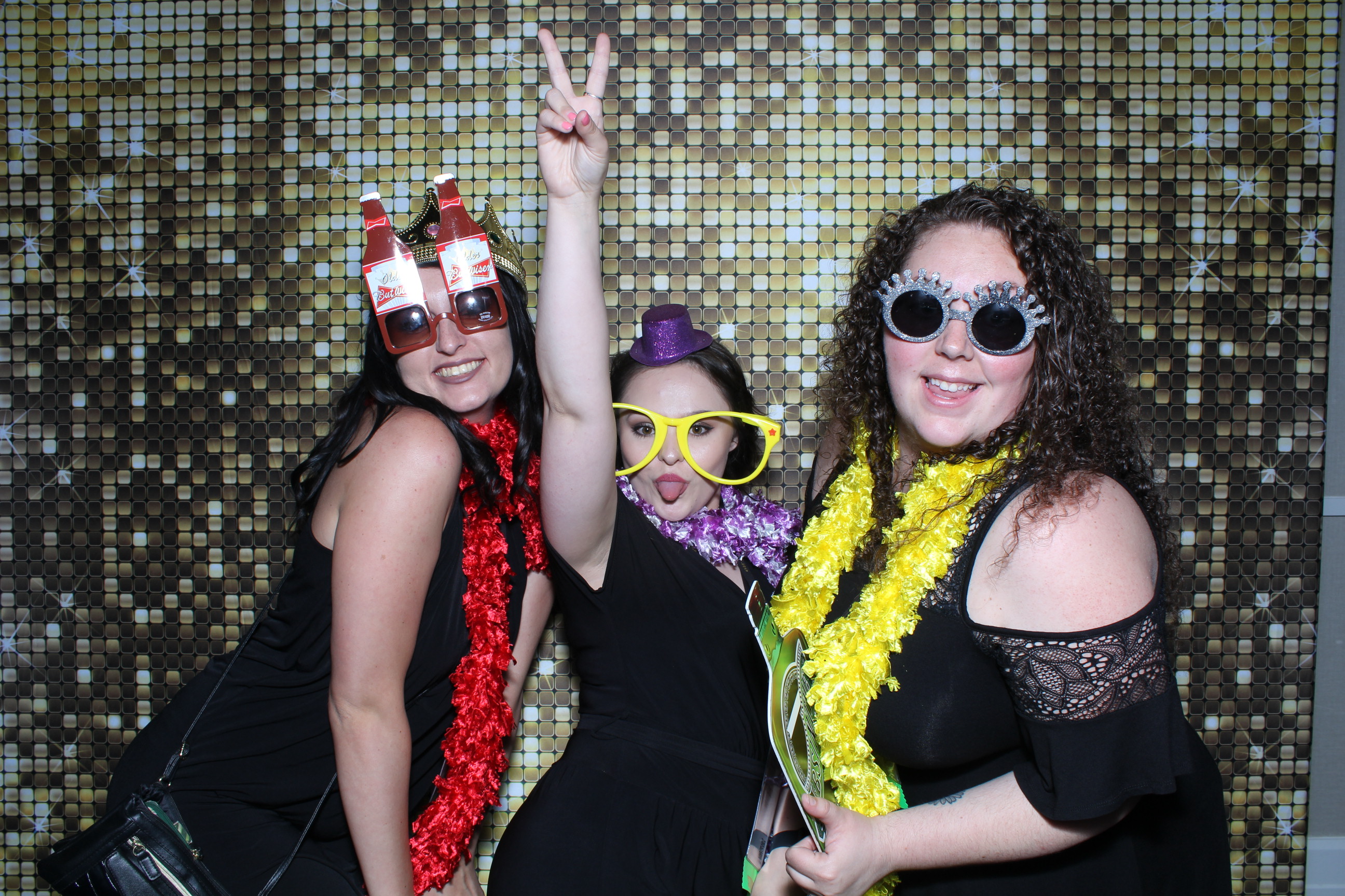 Three women posing for a photo in front of a wall.