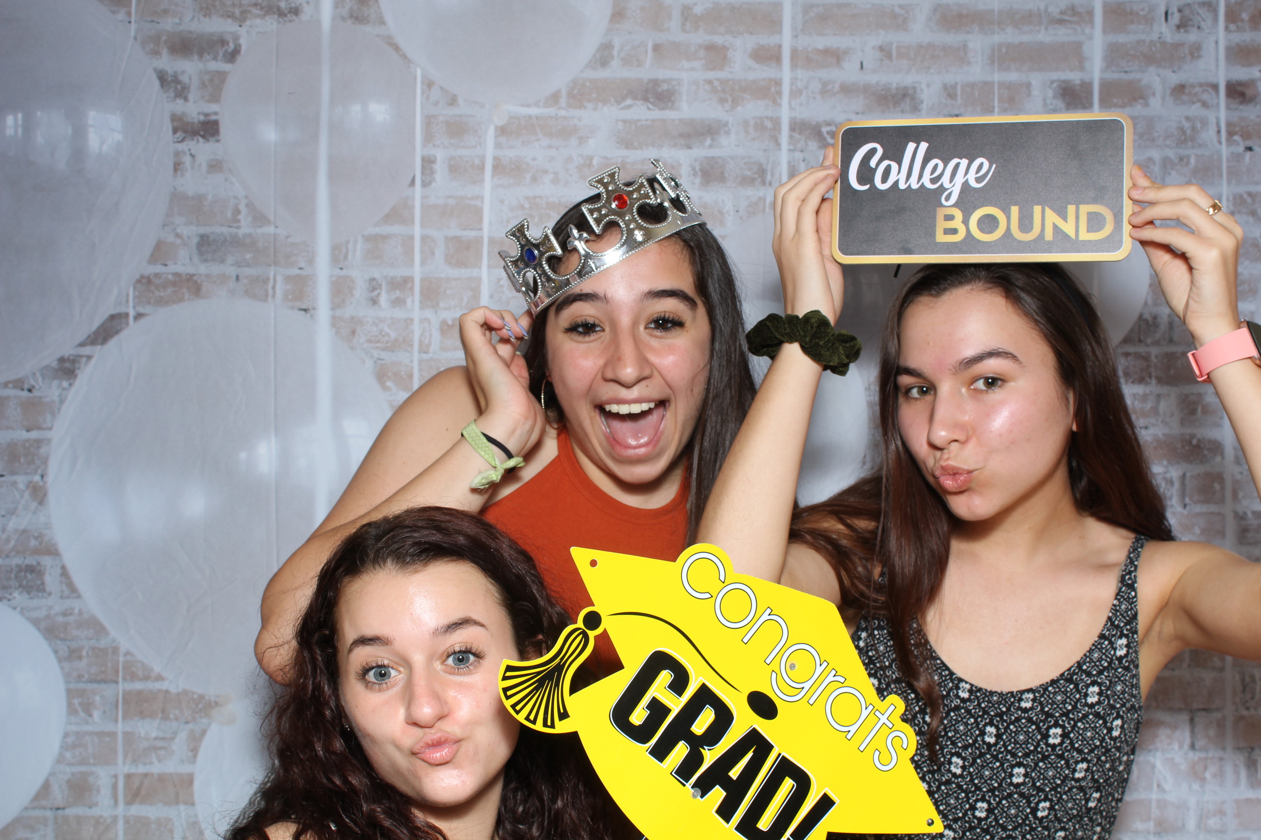 Three girls posing for a picture in front of a wall.