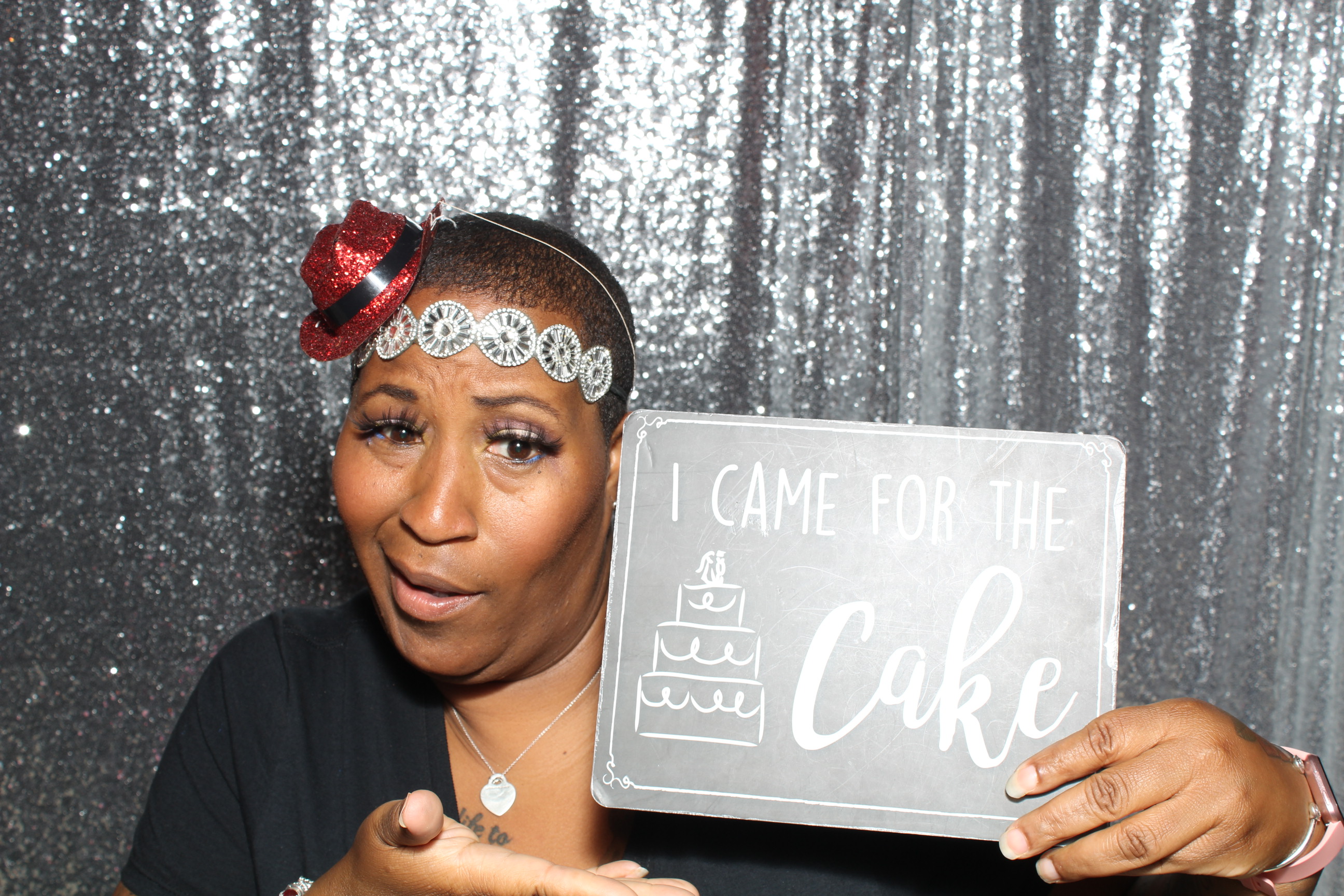 A woman holding up a cake sign in front of a silver backdrop.