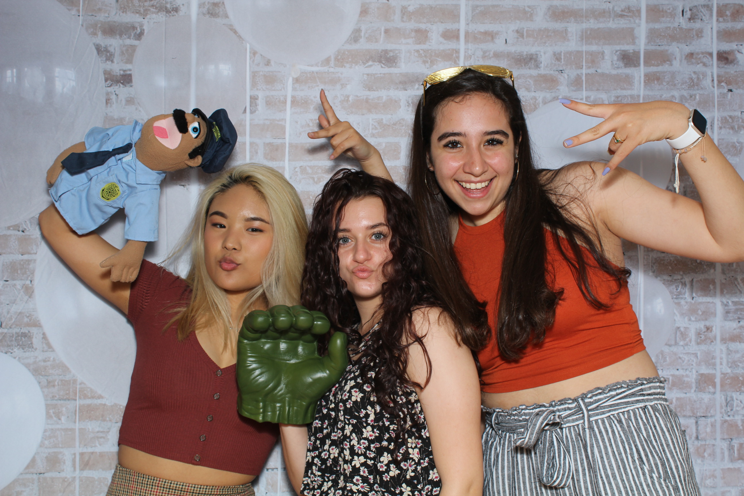 Three women posing for a picture with a toy.