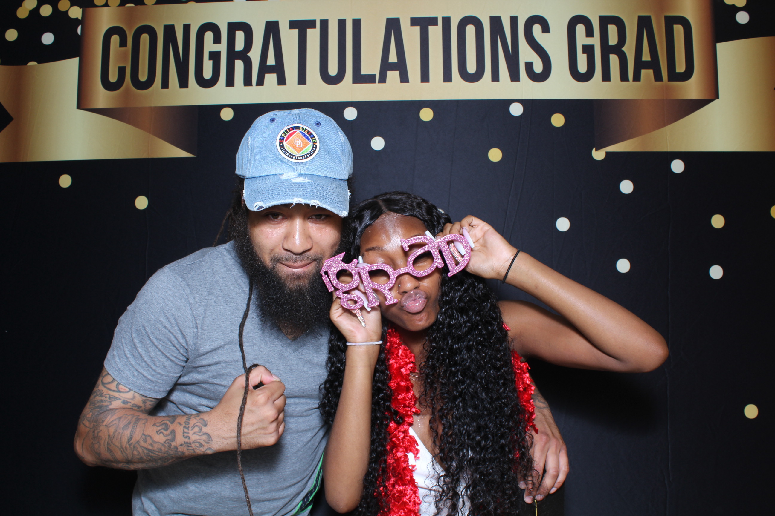 A man and woman posing for a picture in front of a congratulations sign.