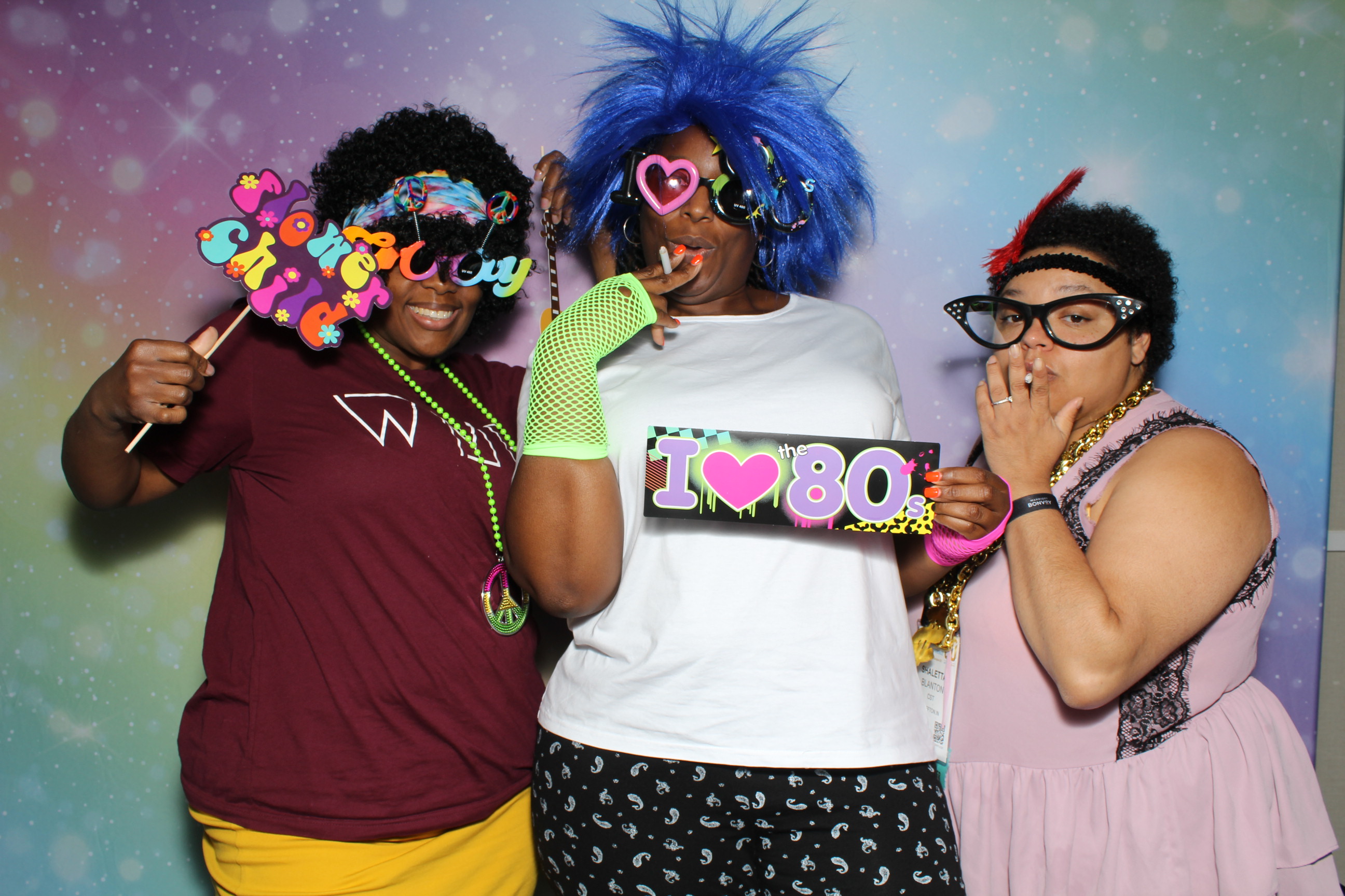 Three women posing for a photo in front of a colorful background.