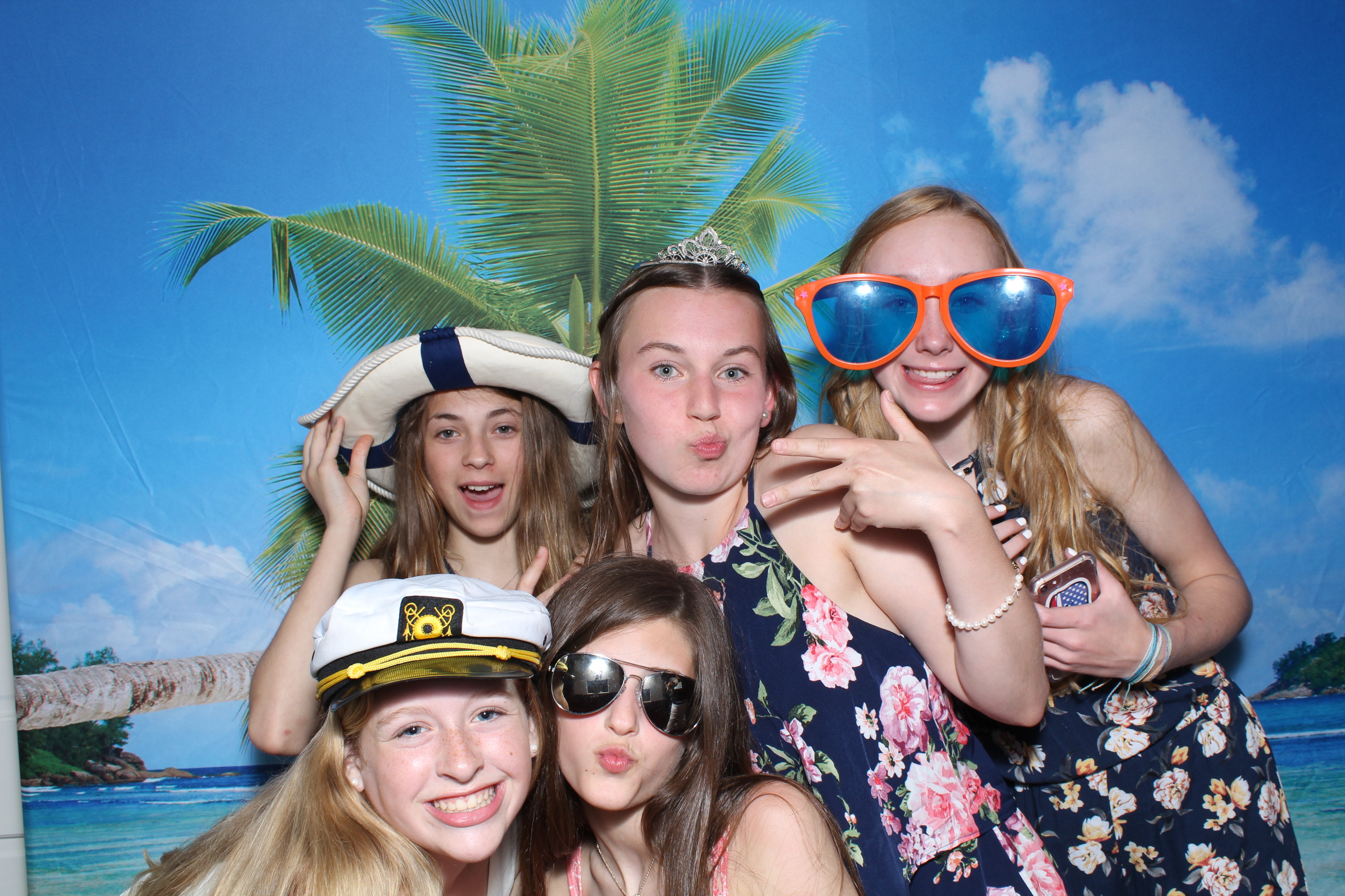 A group of girls posing for the camera in front of palm trees.