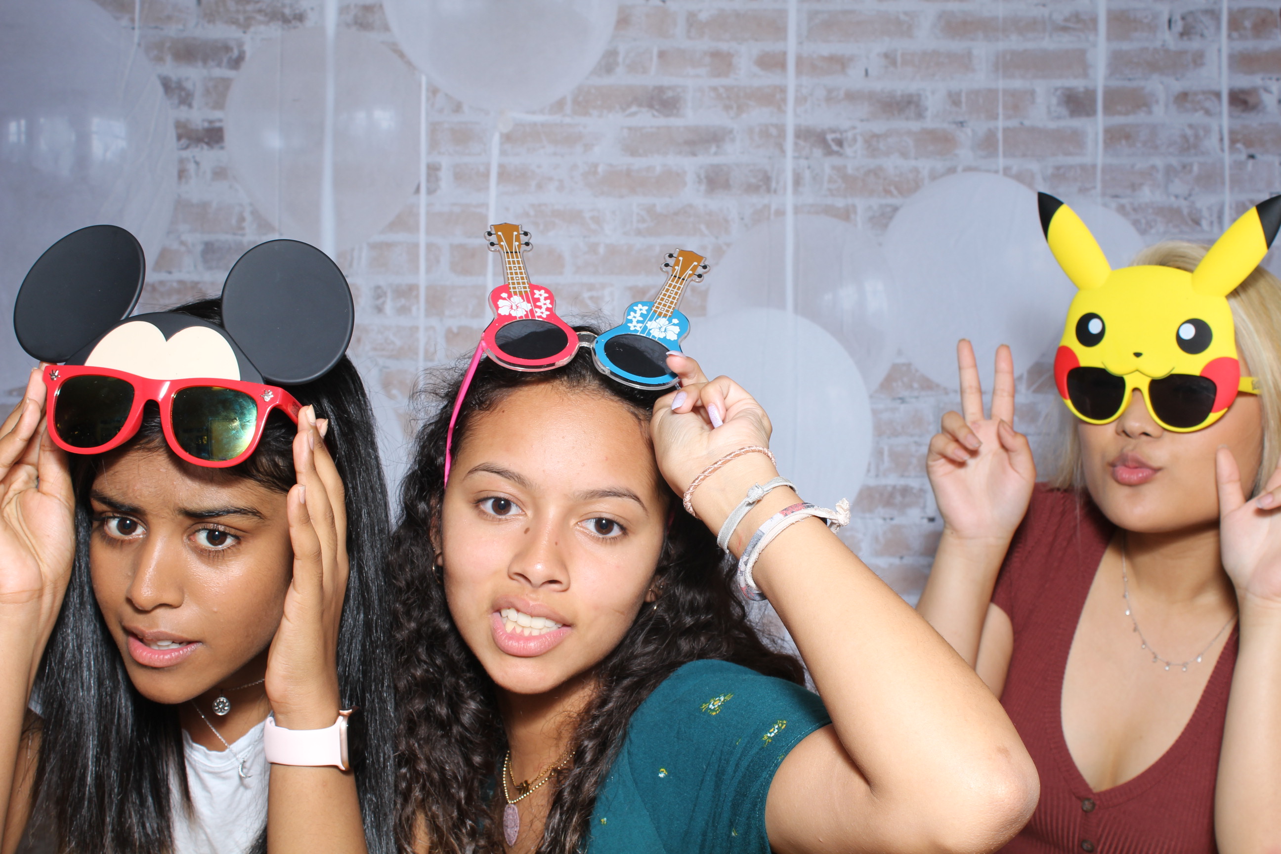 Three young women wearing goofy glasses and mickey mouse ears.