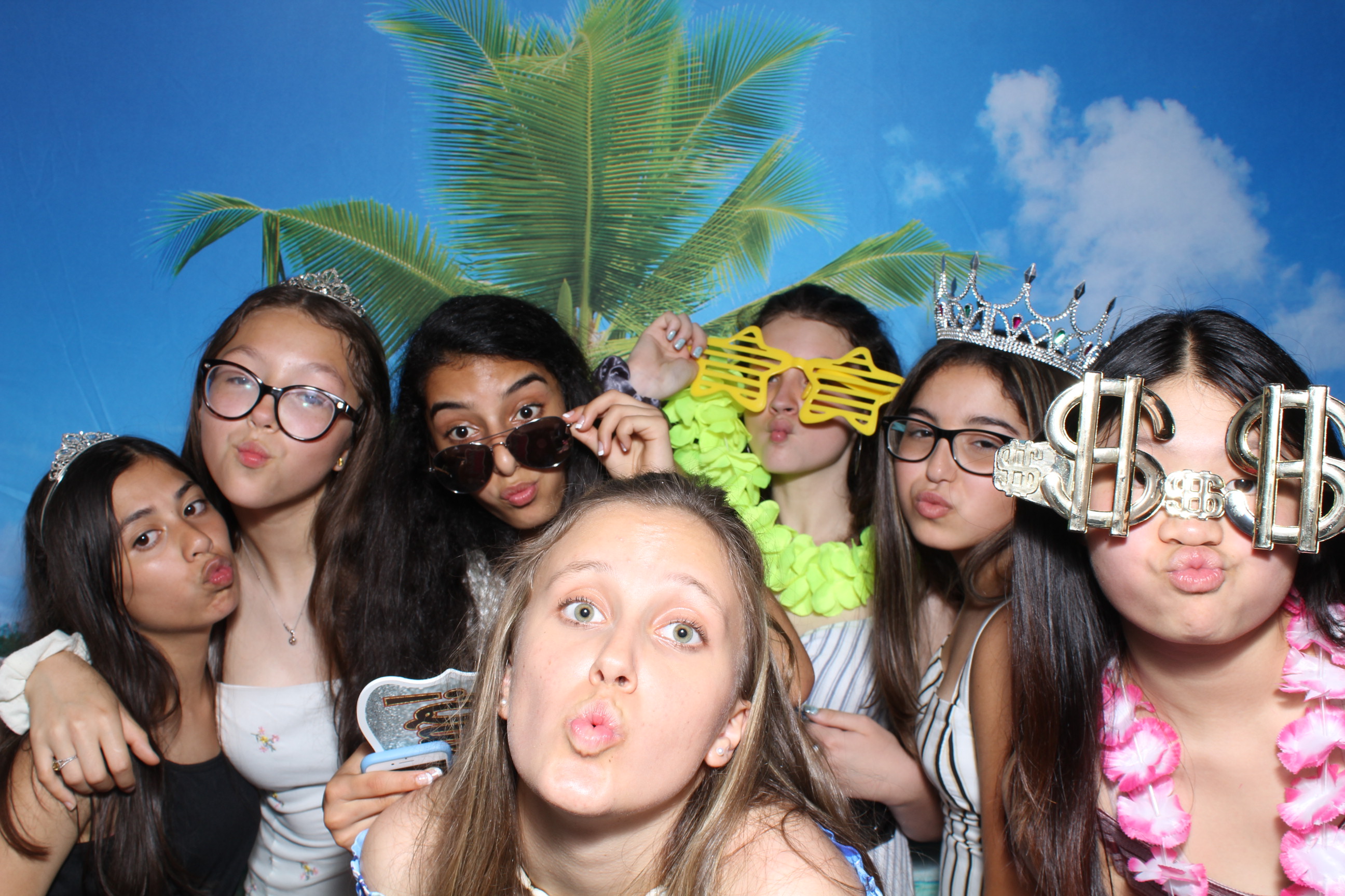 A group of people posing for the camera in front of palm trees.