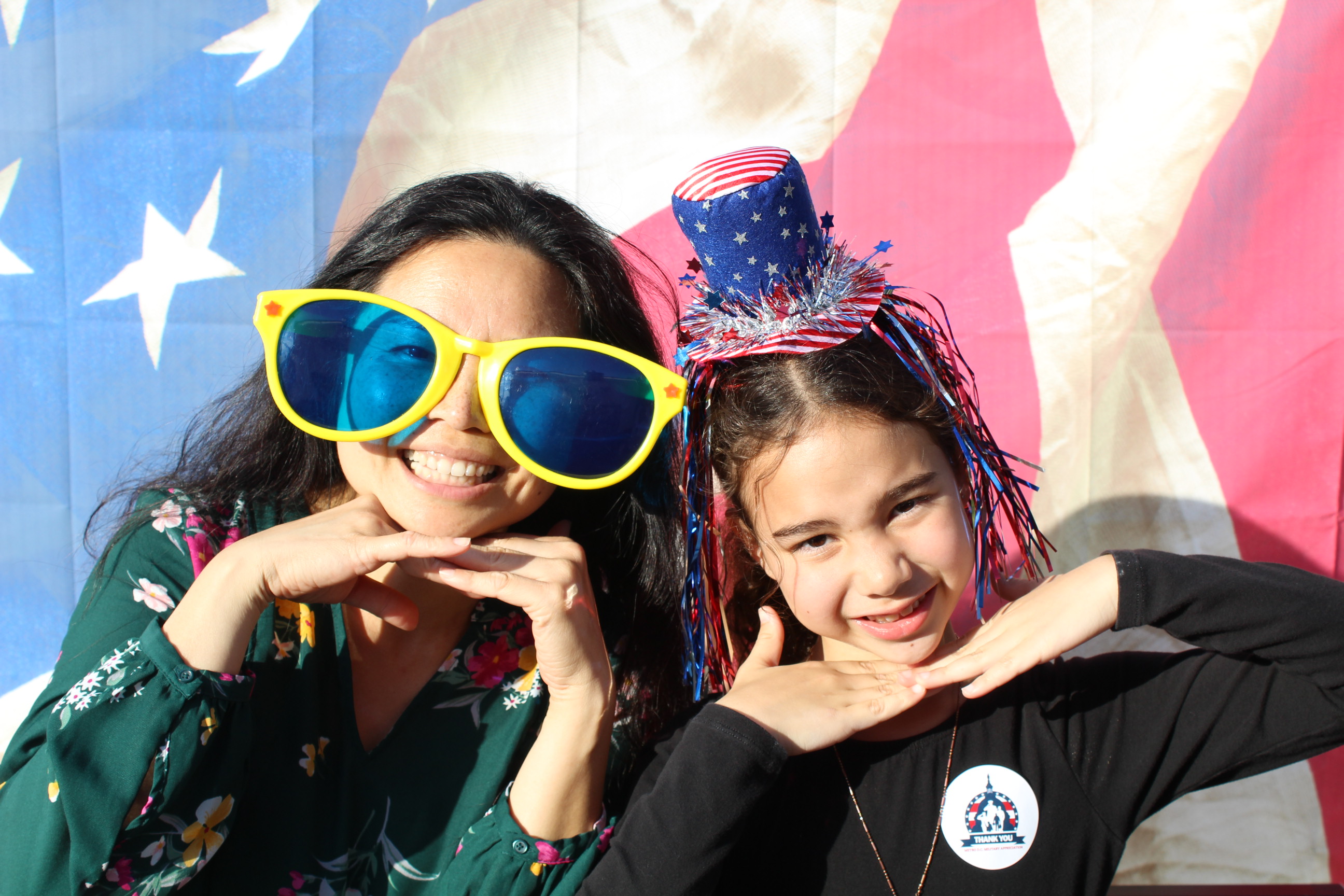 Two girls posing for a picture in front of an american flag.