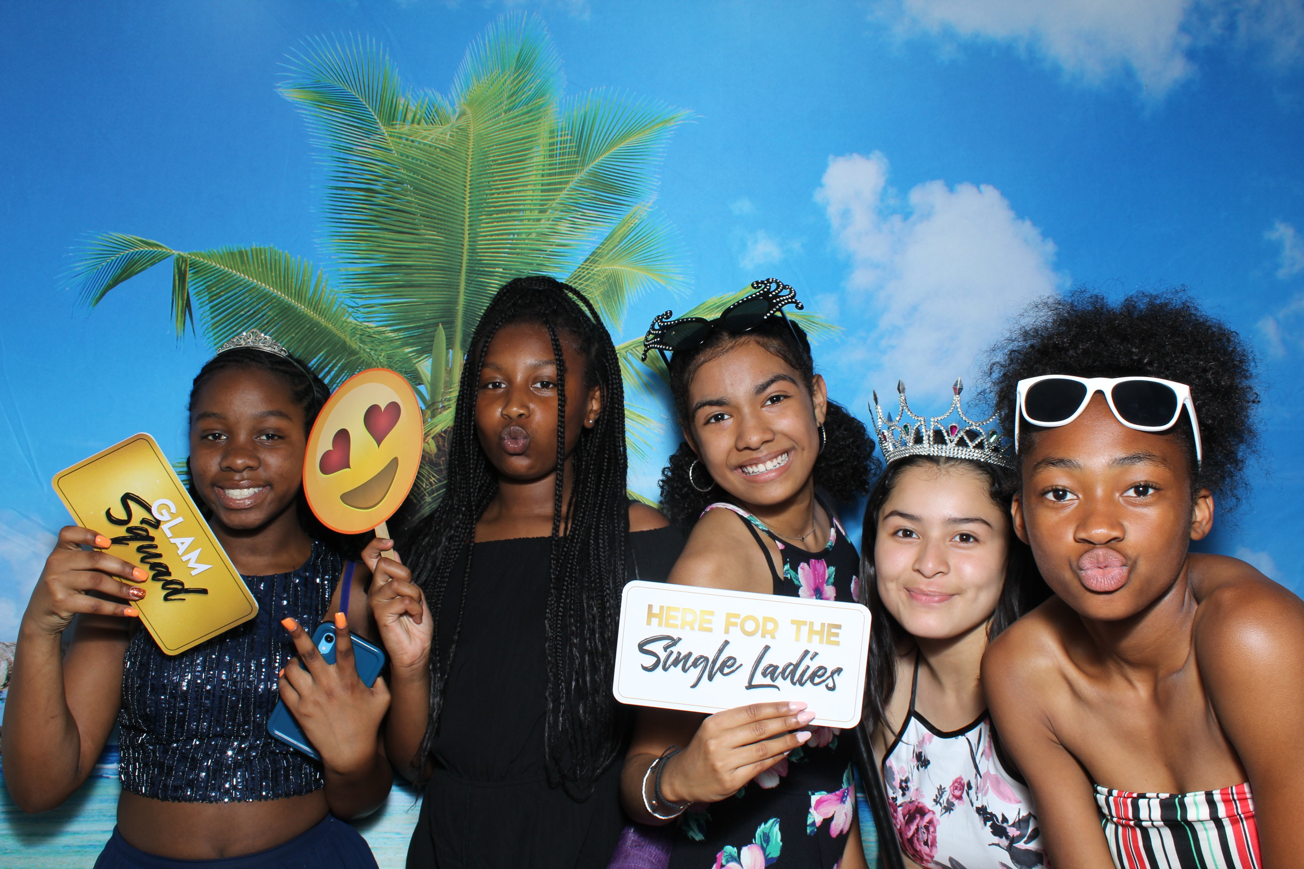 A group of girls holding up signs in front of palm trees.