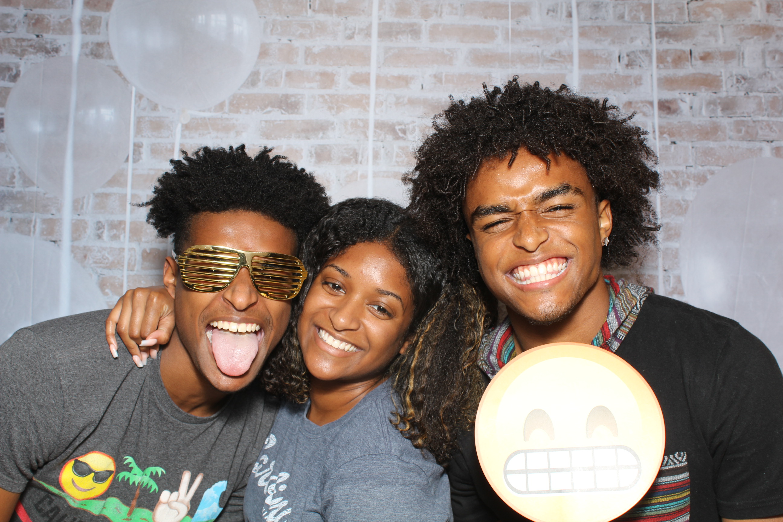 Three people posing for a picture in front of a brick wall.