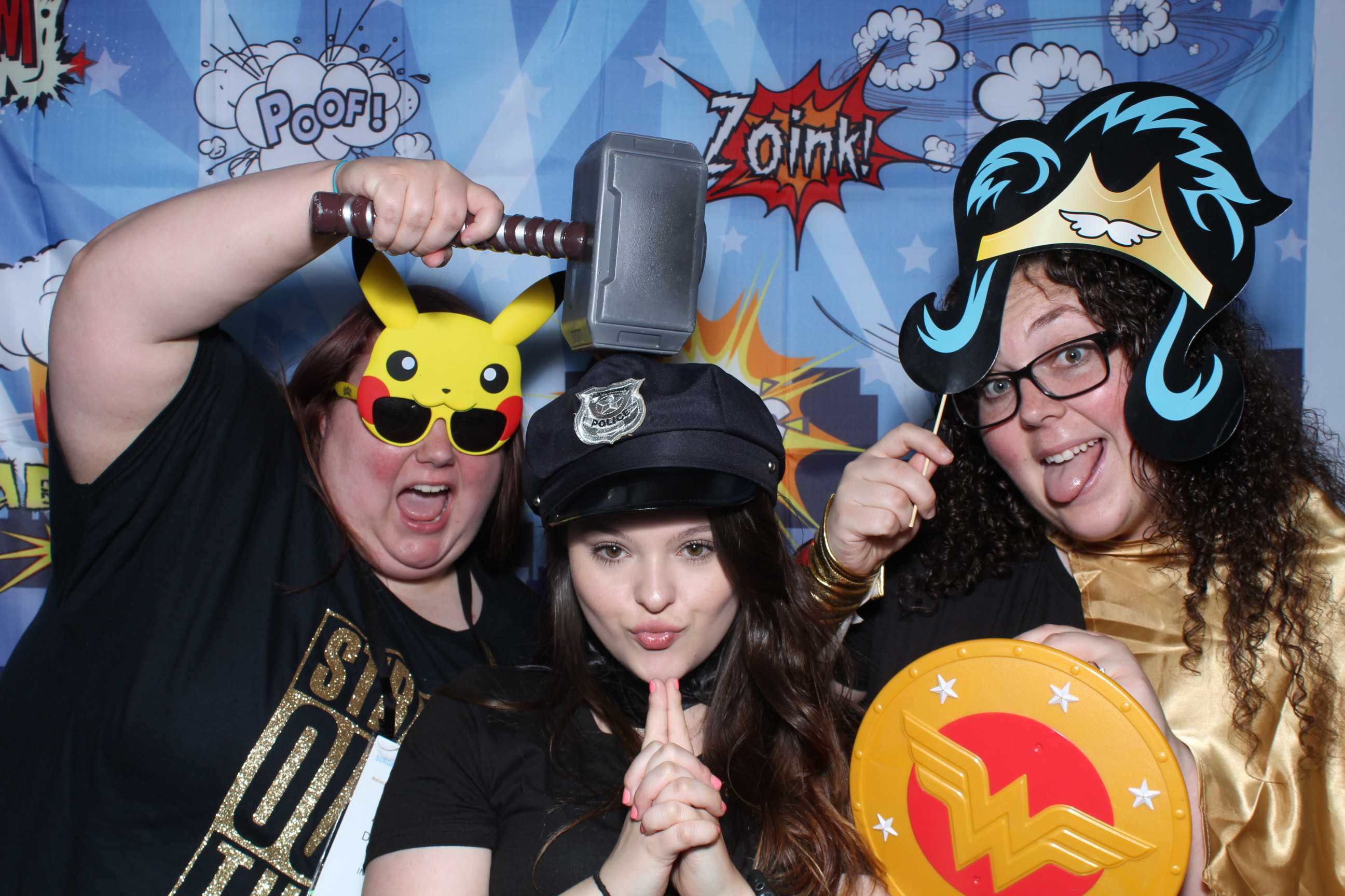Three people posing for a picture in front of comic book background.