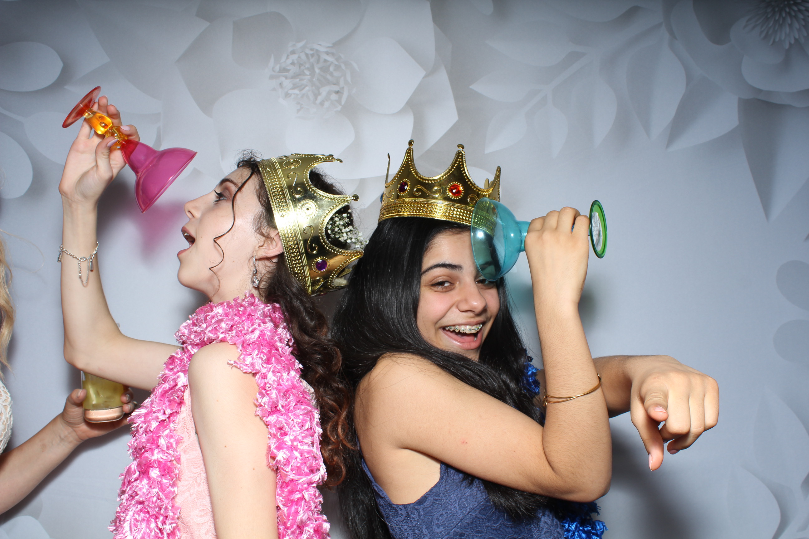Two girls wearing crowns and having fun in a photo booth.
