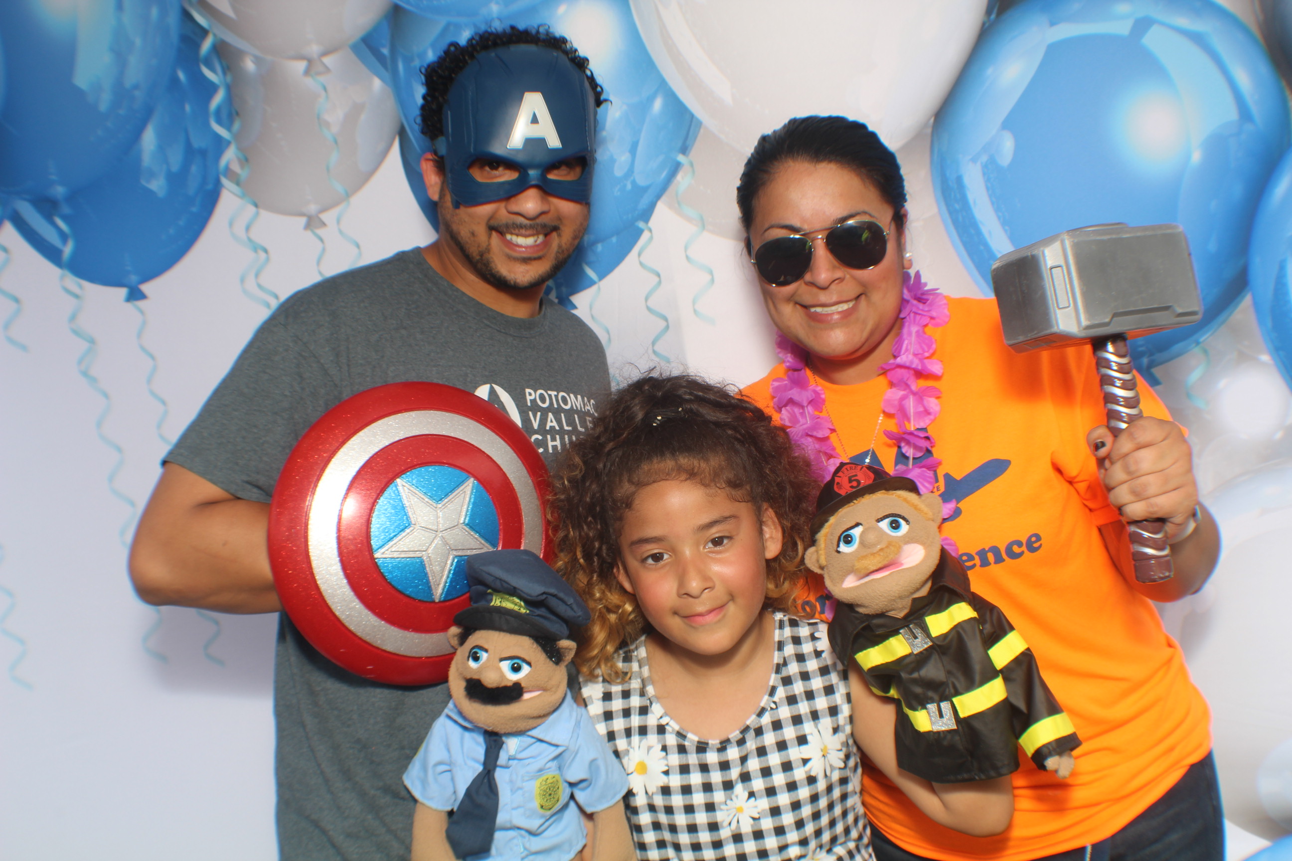 A family posing for the camera in front of balloons.