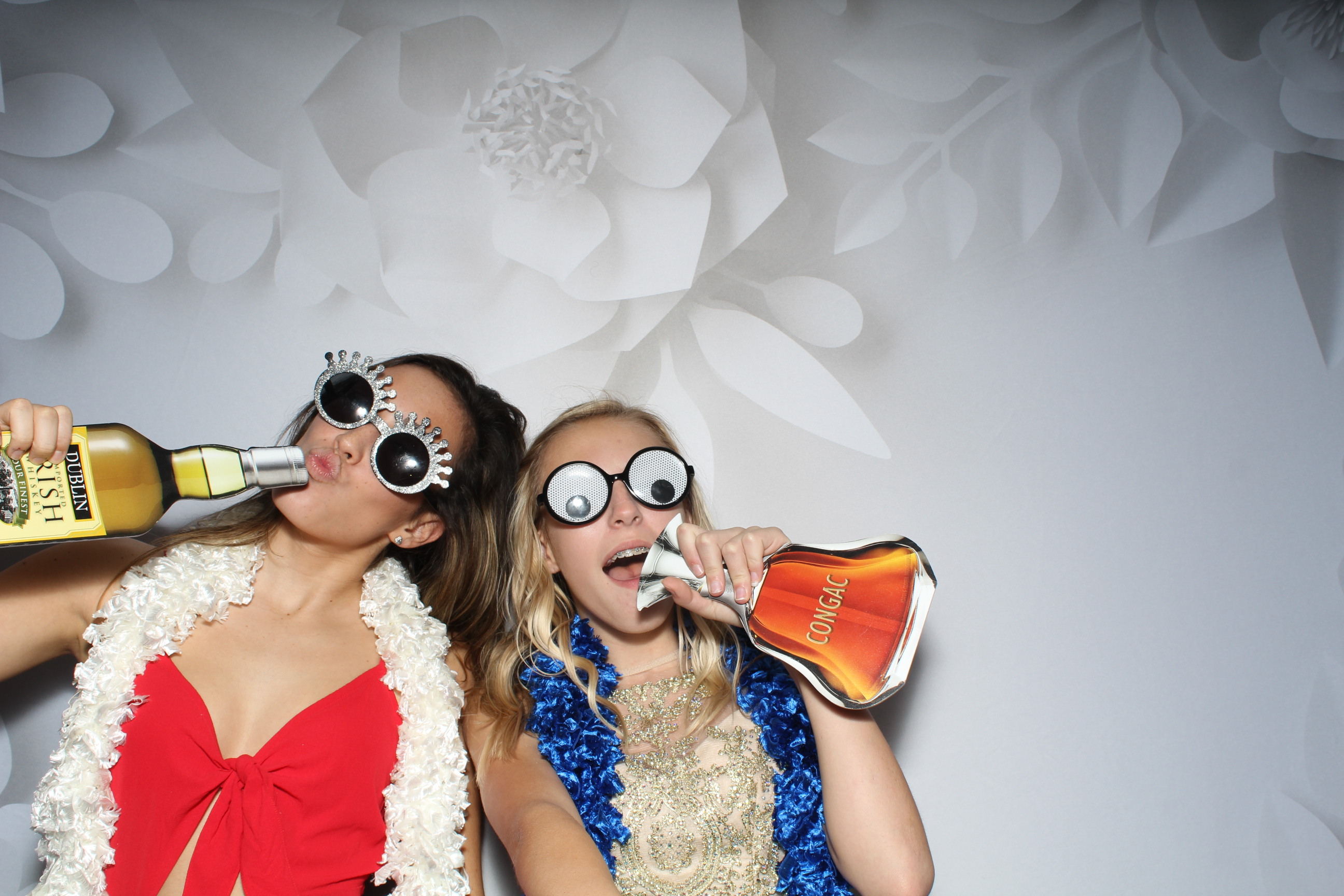 Two women are drinking champagne in a photo booth.
