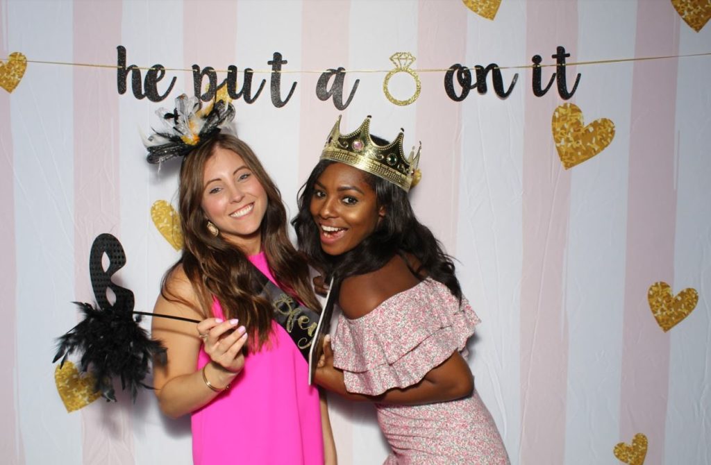 Two women posing for a picture in front of a wall.