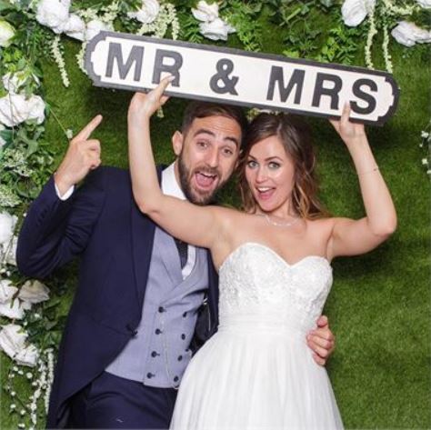 A man and woman holding up a sign that says mr & mrs.