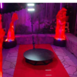 A room with red lighting and statues on the ground.