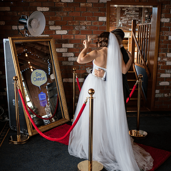 A bride in a white dress standing next to a mirror.